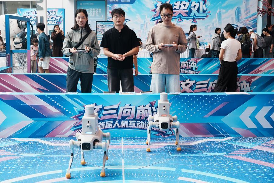 관광객들이 지난 1일 저장성 항저우시 원싼(文三)디지털생활거리에서 로봇개를 조종해 사격 대결을 벌이고 있다. (사진/신화통신)